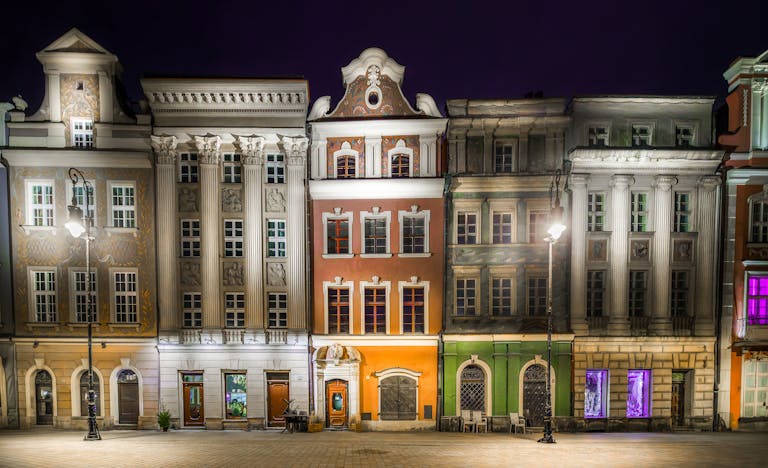 Elegant baroque architecture illuminated at night in Poznań's historic old town.