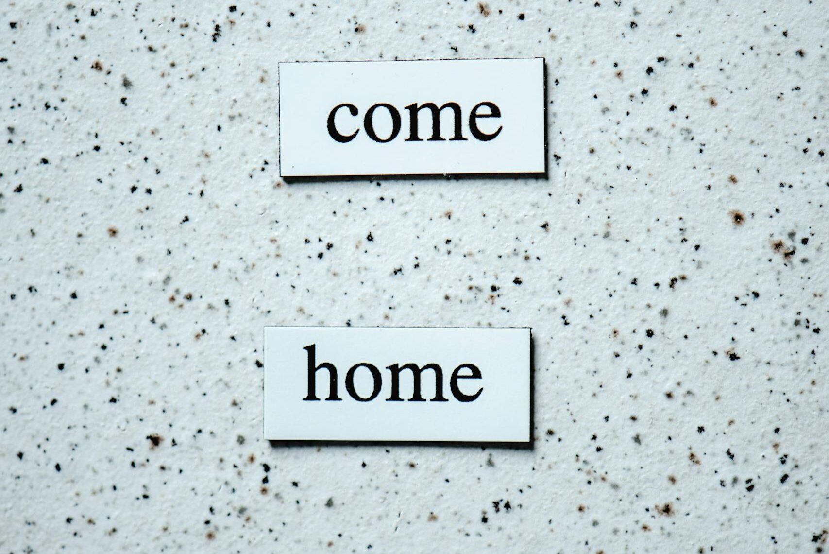 Minimalist photo featuring 'come home' text on a speckled background, ideal for conceptual use.