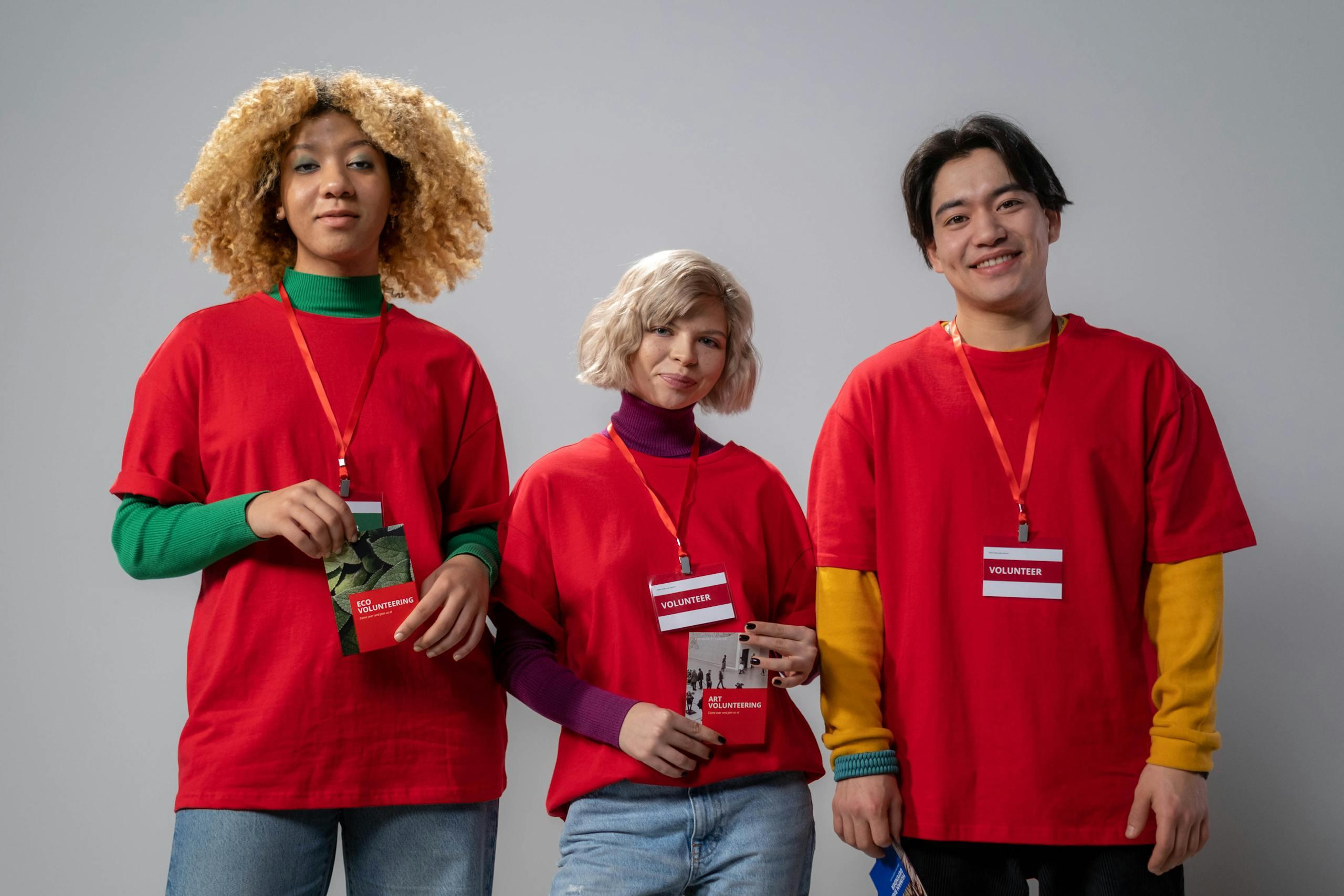 Three cheerful volunteers holding brochures and smiling at the camera.